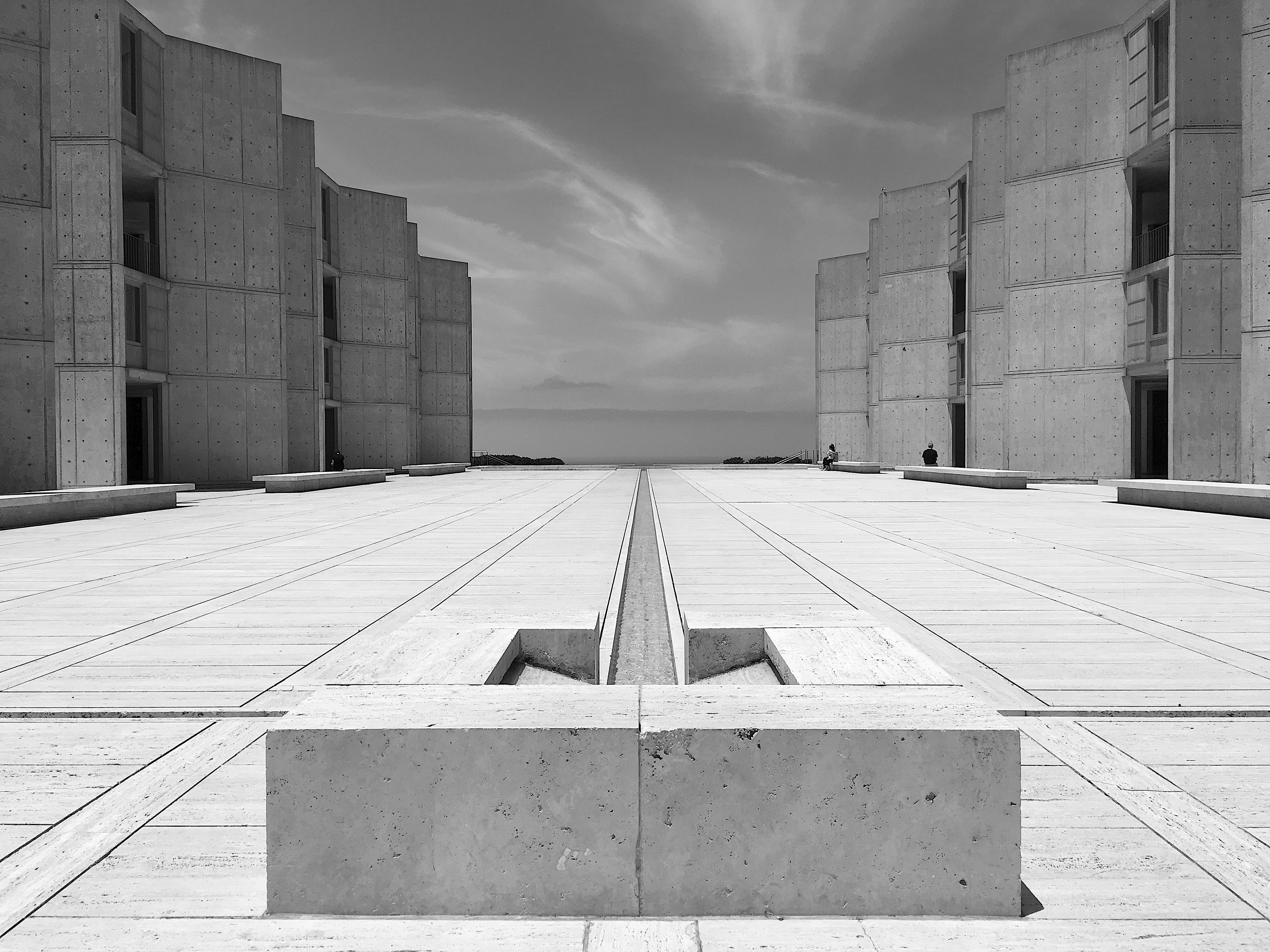 Salk Institute Photograph of the courtyard of the Salk Institute for Biological Studies in La Jolla, San Diego. The Pacific Ocean is visible in the background, with concrete structures on the left and right of the photo.